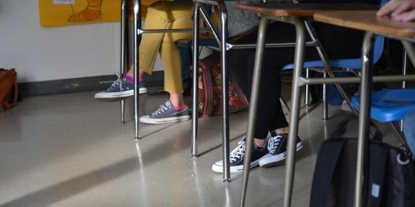 Feet and legs of students sitting at desks in a classroom