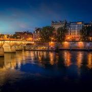 Pont Neuf bridge and Cite island over Seine river at night in Paris